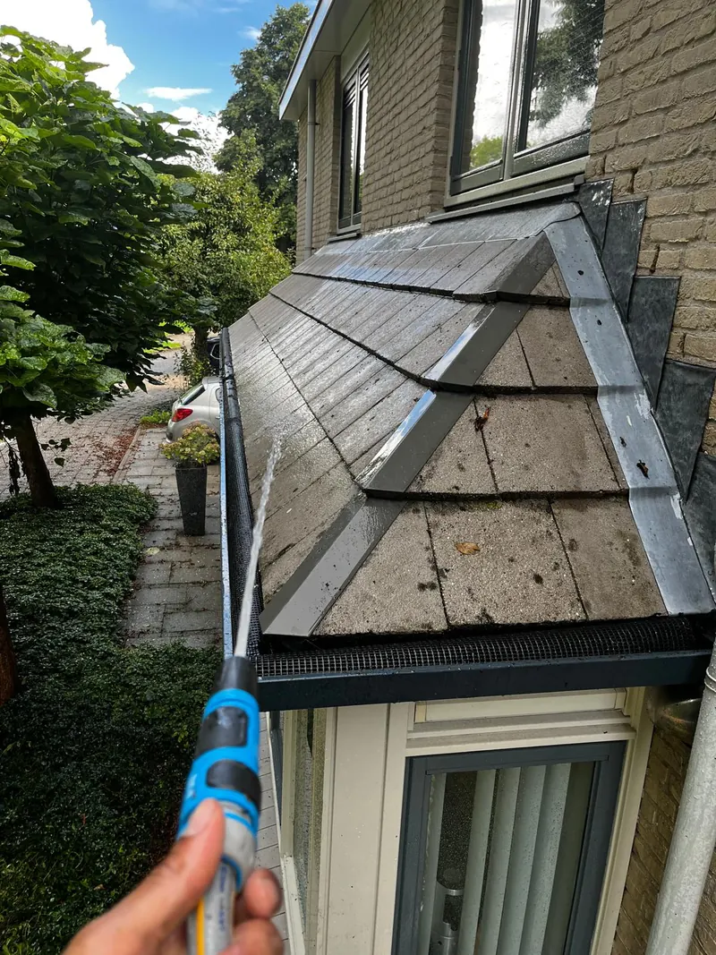 De goot boven een erker doorspoelen met water