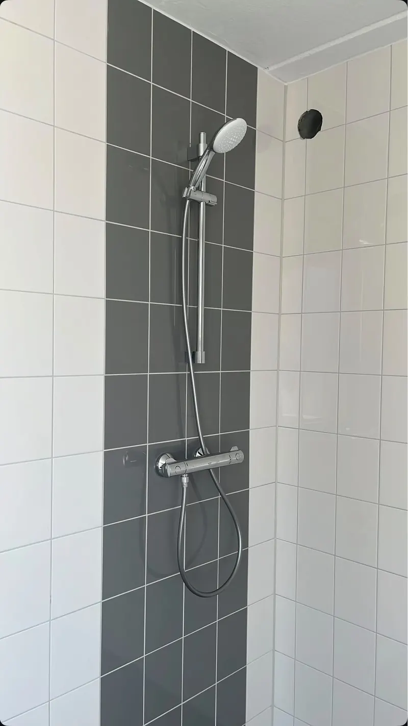 Douche met thermostaatkraan op een grijze tegelstrook