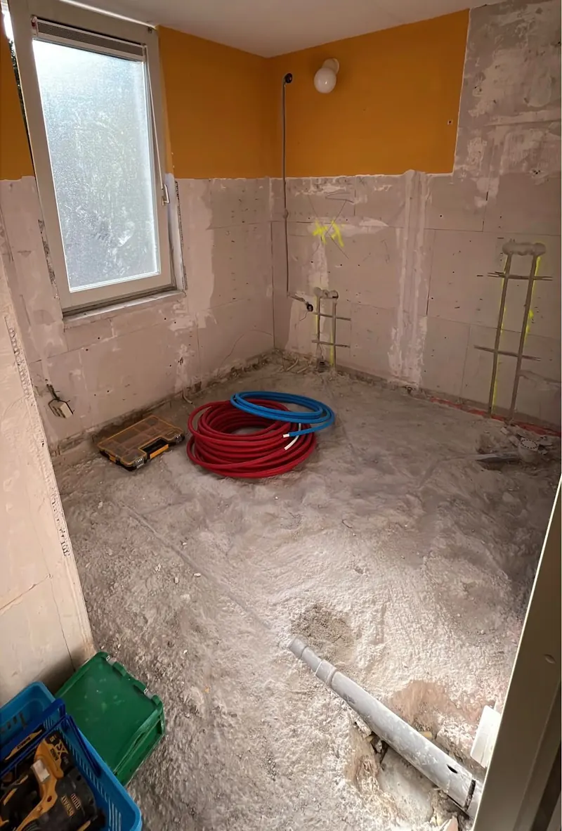 De open badkamer met nieuwe waterleidingen op de vloer