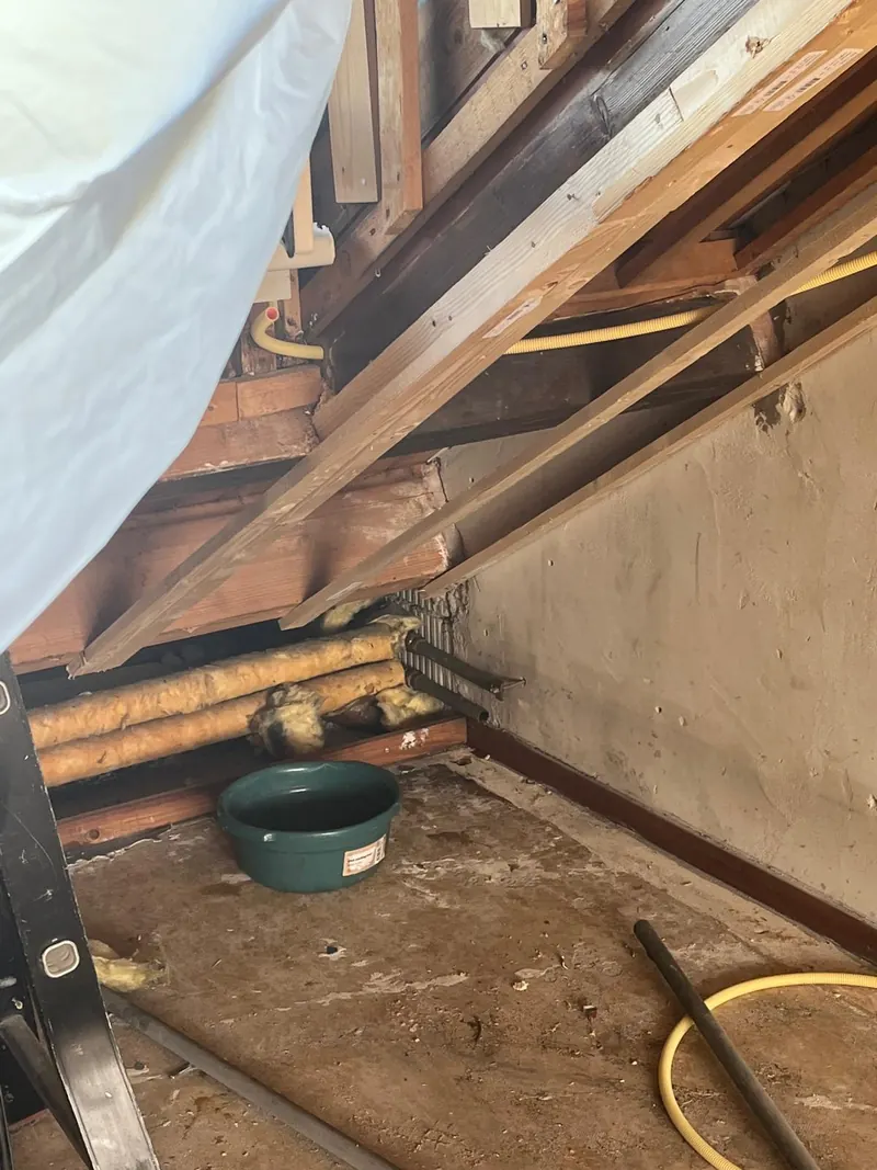 Oude leidingen onder een schuine kap tijdens de renovatie