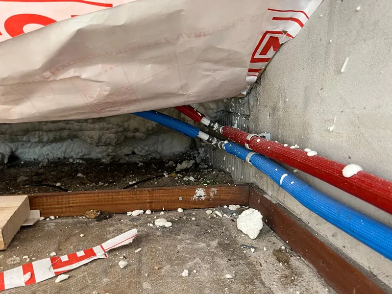 Rode en blauwe leidingen langs de muur tijdens de ruwbouw